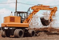 aap-comparing-hydraulic-vs-pneumatic-systems-for-heavy-machinery-1790878784 A yellow excavator at a rural construction site, ready for operation.