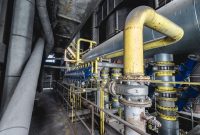 aap-control-valve-sizing-and-cv-calculation-for-industrial-processes-1791990275 Close-up of an intricate industrial pipeline system featuring yellow valves and steel structures inside a factory.