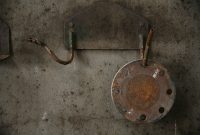 aap-flange-bolt-torque-sequences-and-gasket-selection-for-high-pressure-systems-1791640819 Rusty metal fixtures on a weathered concrete wall, showcasing industrial decay.