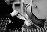 aap-how-to-reduce-downtime-in-manufacturing-production-lines-1790892940 Man working with machinery in a factory setting, showcasing industrial production.