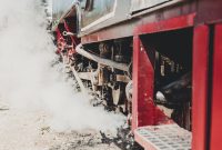 Detailed view of a vintage steam locomotive engine with steam and smoke outdoors.