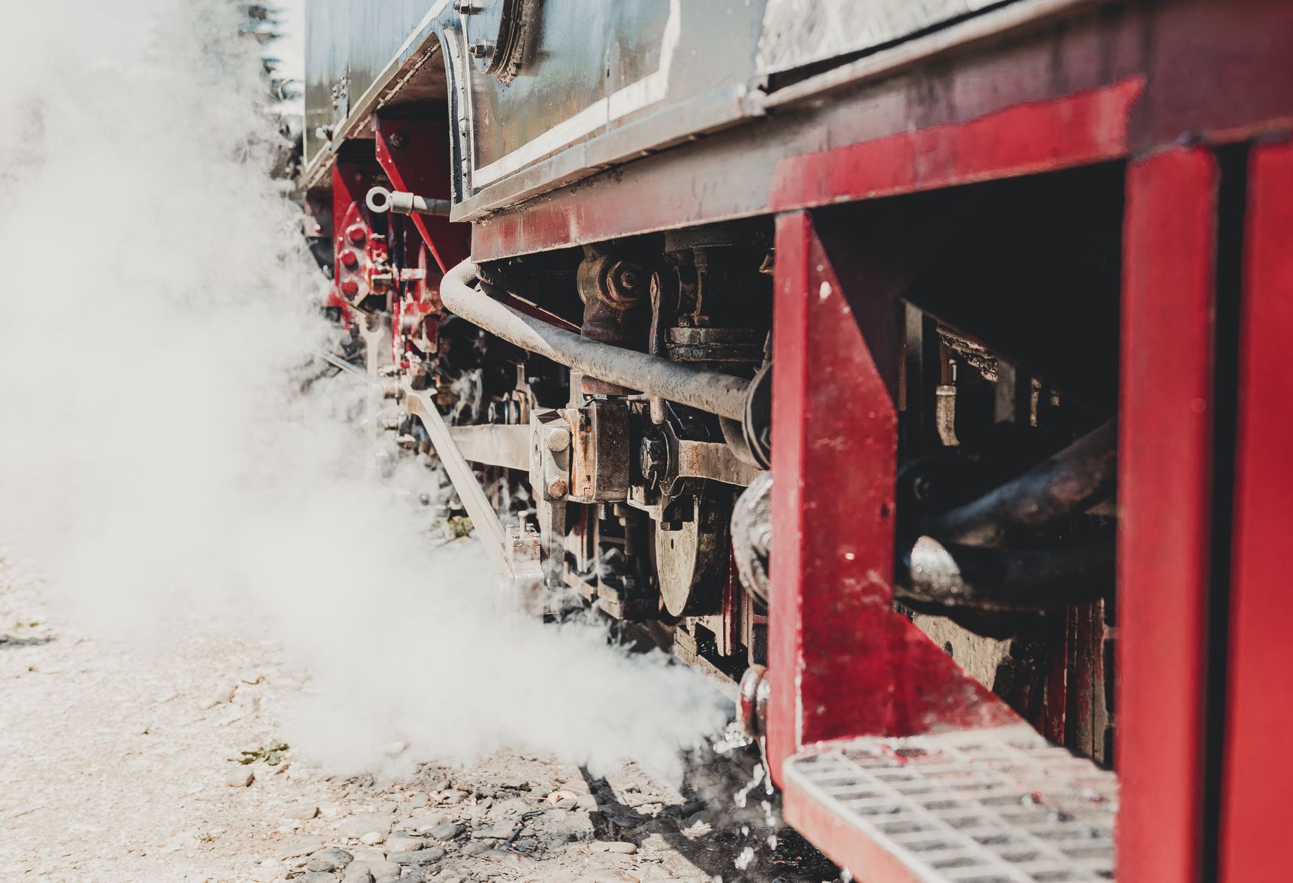 Detailed view of a vintage steam locomotive engine with steam and smoke outdoors.