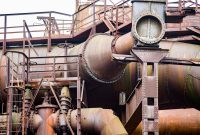 aap-root-cause-analysis-of-industrial-pipe-fatigue-failures-1791727219 Detailed view of a rusty industrial pipe system showcasing robust metal construction and aged textures.
