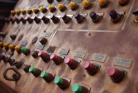 aap-understanding-iiot-implementation-costs-for-manufacturing-plants-1790875209 Vintage control panel with colorful buttons and industrial labels.