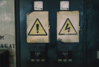 Close-up of industrial warning signs on an aged electrical panel.